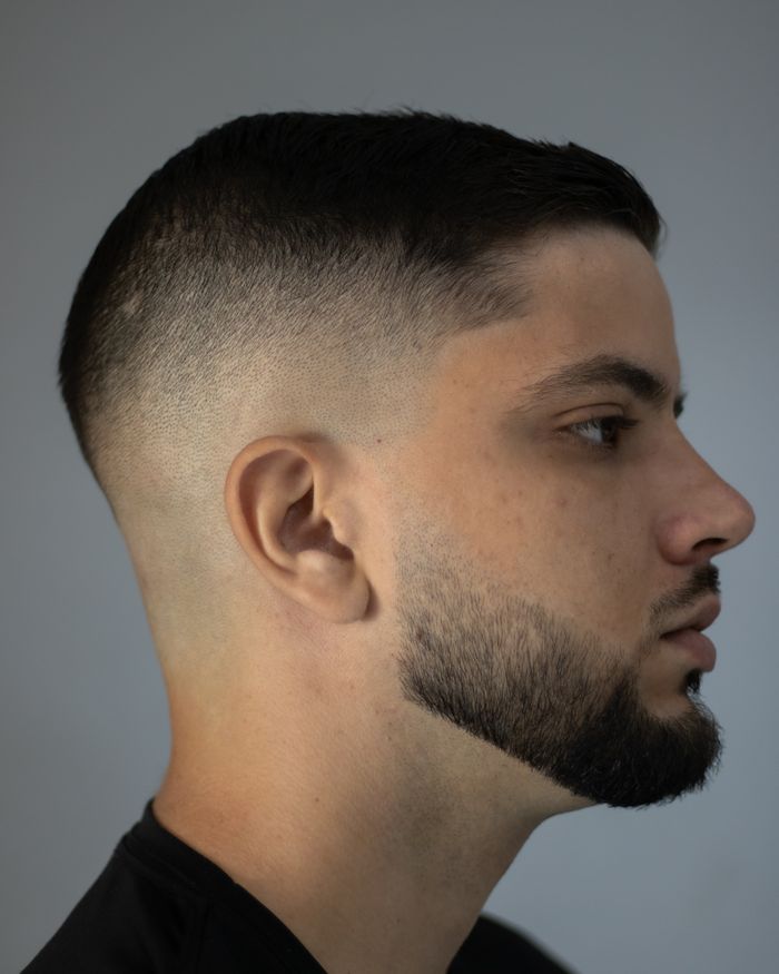 Zijaanzicht van een man met een high skin fade en een kort getrimde baard