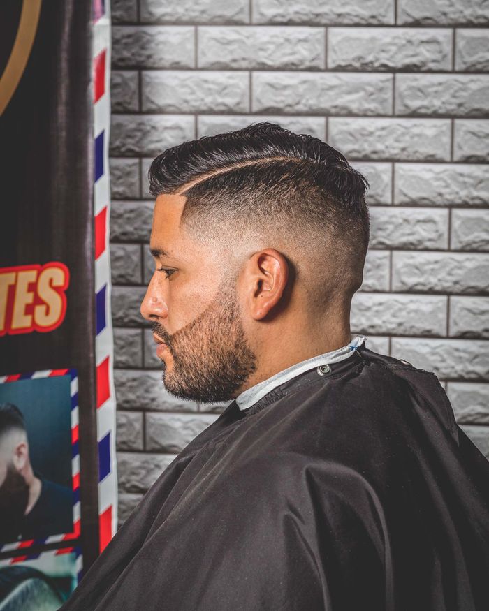 Man met een mid fade en een geschoren scheiding in de barbershop