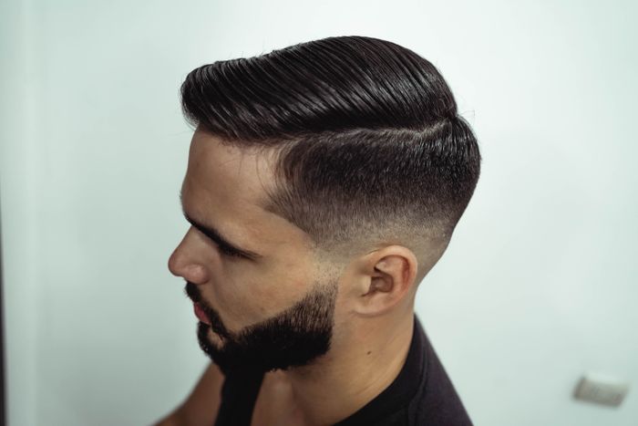 Man met langer haar bovenop in een side part en een fade aan de zijkant